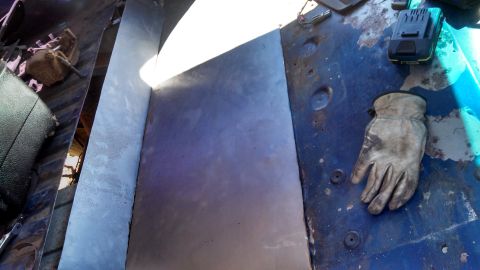 1979 Ford Bronco - A work glove rests on the blue metal interior of a vehicle, next to a newly installed panel.