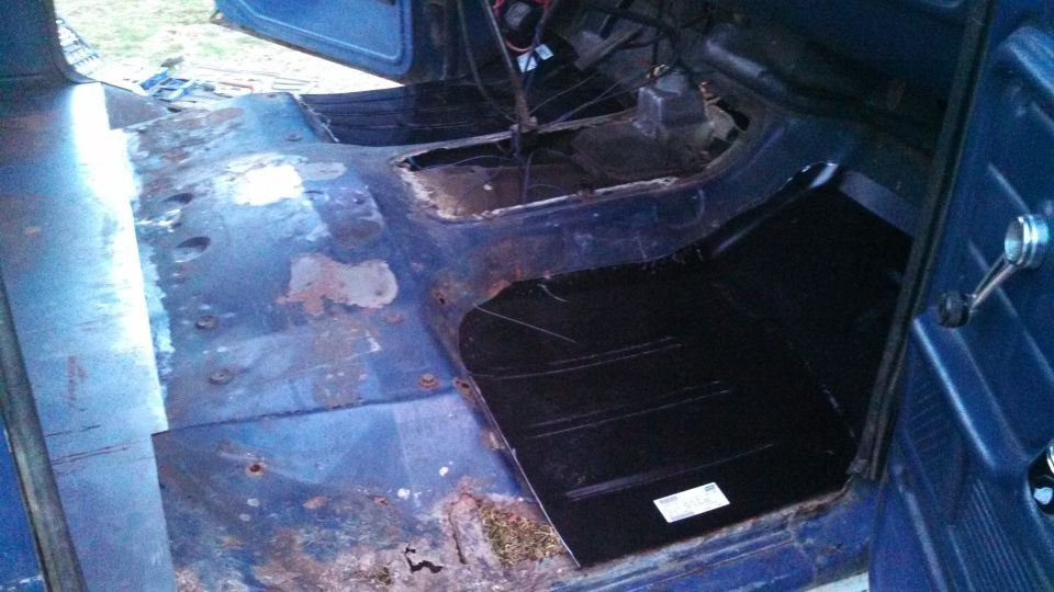 Blue vehicle interior with rusted floorboards and new black floor panel installed