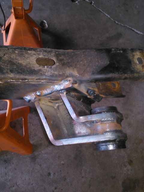 1968 Ford Bronco - Close-up of a custom welded frame modification, likely for a suspension upgrade, with orange jack stands visible.