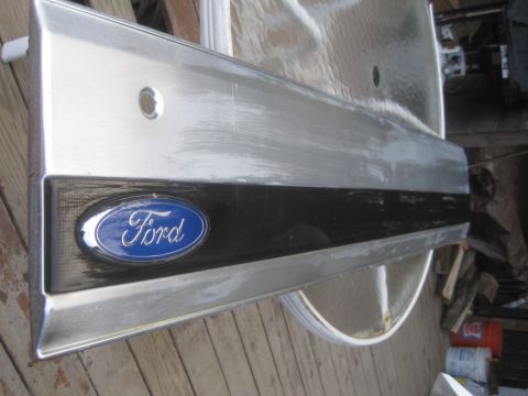1993 Ford Bronco - Ford emblem on a metal trim piece, likely from a vehicle part.