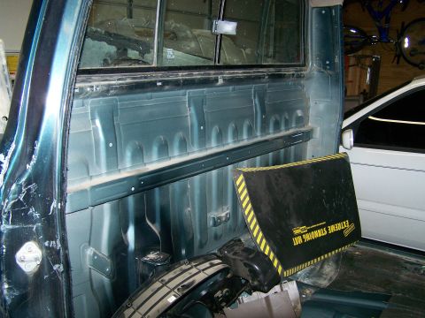 1988 Suzuki Samurai - Interior view of a pickup truck bed, showing the side paneling and floor. A mat is placed on the floor.