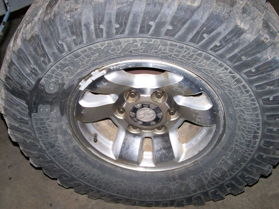 Close-up of a large off-road tire with a chrome alloy wheel. Tire has aggressive tread pattern