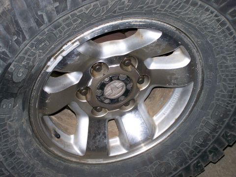 1988 Suzuki Samurai - A close-up view of a vehicle's tire and wheel assembly, showing balance weights attached to the rim.
