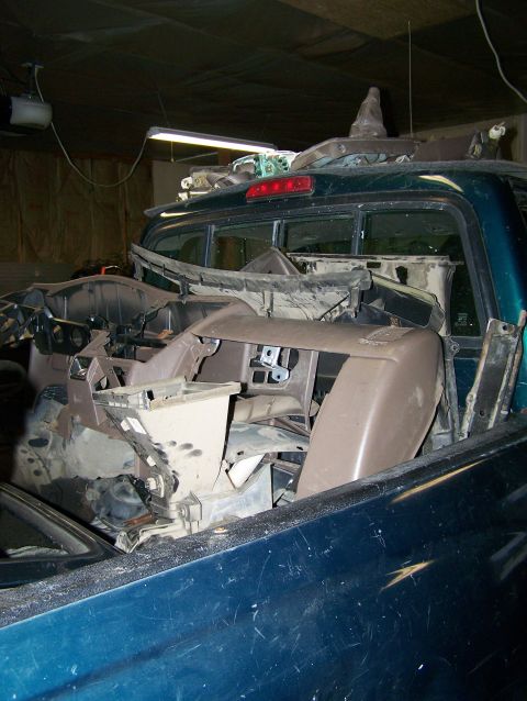 1988 Suzuki Samurai - Disassembled dashboard components are piled in the bed of a dark green pickup truck, obscuring the interior.
