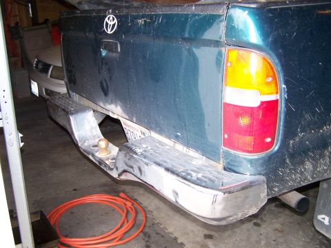 1988 Suzuki Samurai - The rear of a teal pickup truck is visible, with another vehicle parked ahead of it.