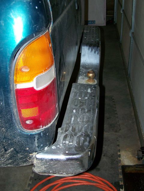 1988 Suzuki Samurai - Rear view of a teal SUV's bumper and taillight, showing a tow hitch and textured pattern.