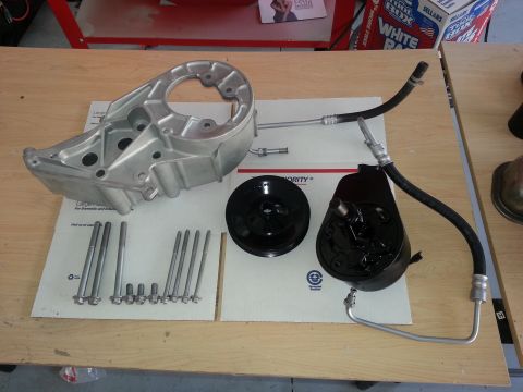 1994 Ford Bronco - Various parts for a vehicle's power steering system are arranged on a wooden surface.