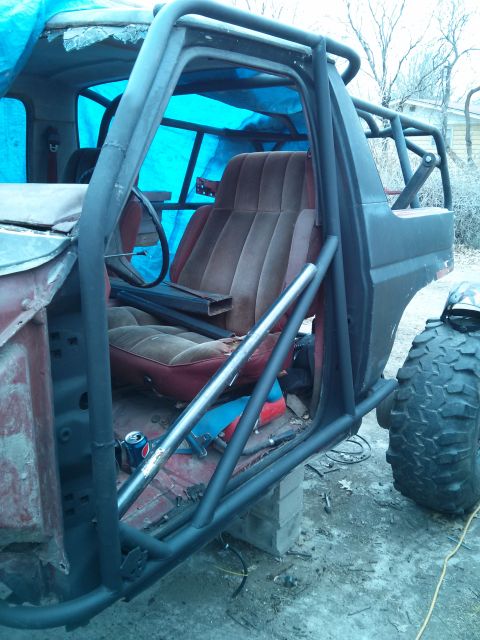1986 Ford Bronco - This vehicle appears to be undergoing modifications, possibly for off-road use, with a prominent roll cage installed.