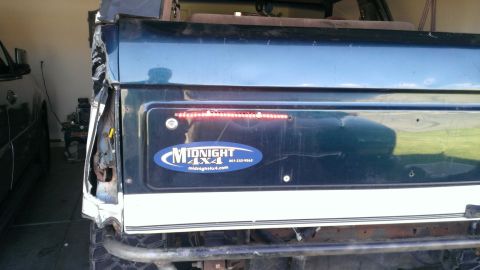 1994 Ford Bronco - The rear of a Ford Bronco shows damage to the tail light assembly and a "Midnight 4x4" decal.