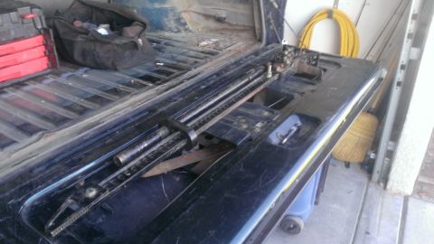 1994 Ford Bronco - A jack and tools are stored in the open tailgate of a truck.