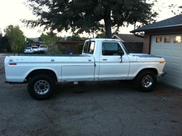 1977 Ford F-350 pickup truck, side view, parked on asphalt next to a garage