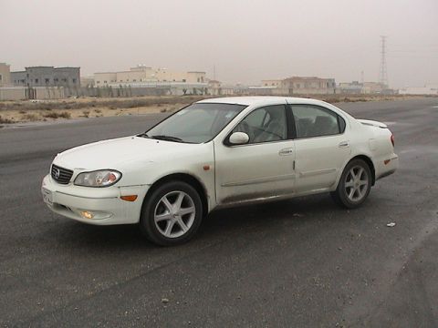 2004 Nissan Maxima - A white 2004 Nissan Maxima is parked outdoors on a paved surface with buildings in the distance.