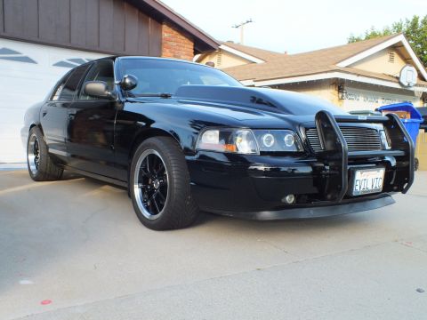 2003 Ford Crown Victoria - This black 2003 Ford Crown Victoria features a prominent push bar and a distinctive hood scoop.
