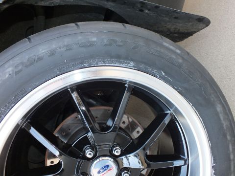 2003 Ford Crown Victoria - A close-up view of a performance tire and wheel assembly, a Ford Racing center cap and a visible brake rotor.