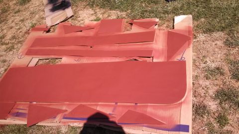 1979 Ford Bronco - Car door and trim pieces are laid out on cardboard and painted red.