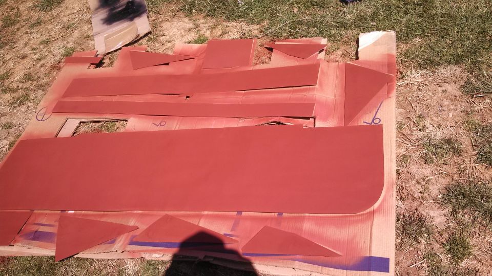 Red painted car door and trim pieces laid out on cardboard