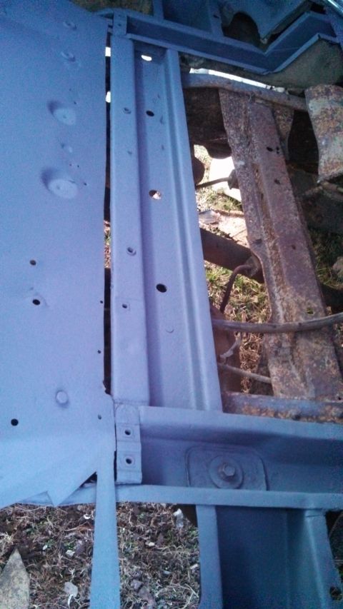 1979 Ford Bronco - Close-up view of a vehicle's frame and floor pan, showing fresh paint over rusted metal parts.