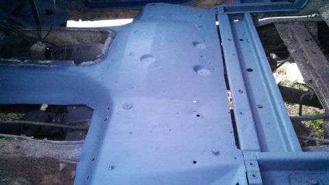 1979 Ford Bronco - The floor pan and frame of a vehicle, showing signs of rust and primer application.