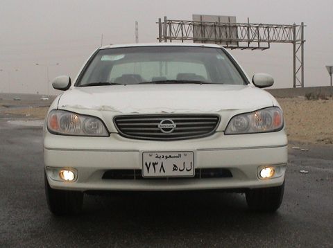 2004 Nissan Maxima - Front view of a white 2004 Nissan Maxima with its headlights and fog lights illuminated.