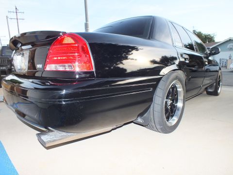 2003 Ford Crown Victoria - Rear view of a black 2003 Ford Crown Victoria showing custom wheels and a spoiler.