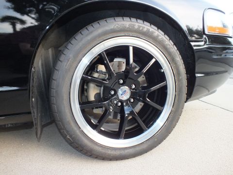 2003 Ford Crown Victoria - Front wheel and tire detail on a black vehicle, aftermarket wheels and performance tires.