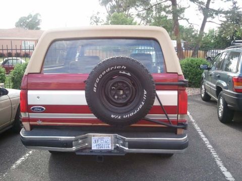 1988 Ford Bronco - Rear view of a red and tan 1988 Ford Bronco, showing its spare tire and license plate.