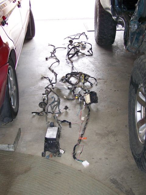 1988 Suzuki Samurai - Vehicle wiring harness spread out on the floor next to a red car and a dark SUV.