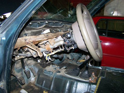 1988 Suzuki Samurai - The interior of a vehicle is shown with the dashboard removed, revealing the steering column and pedals.