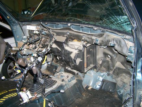 1988 Suzuki Samurai - The interior of a vehicle shows extensive damage and exposed wiring, with a cracked windshield.