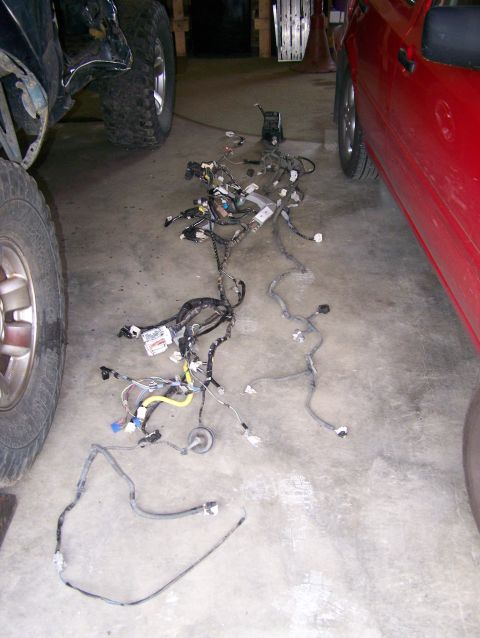 1988 Suzuki Samurai - A complex vehicle wiring harness lies on the floor, partially obscured by two vehicles.