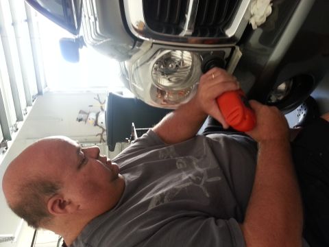 2007 Ford F-250 - A person is shown working on the front headlight of a vehicle, with a chrome grille above.