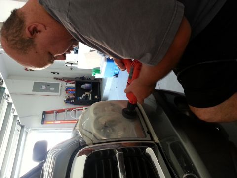2007 Ford F-250 - A person is using a drill with a polishing attachment to restore a cloudy headlight on a vehicle.