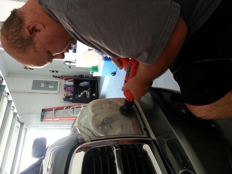 Man polishing a headlight with a drill