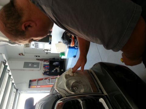 Man cleaning the headlight of a 2007 Ford F-250. Grille details visible