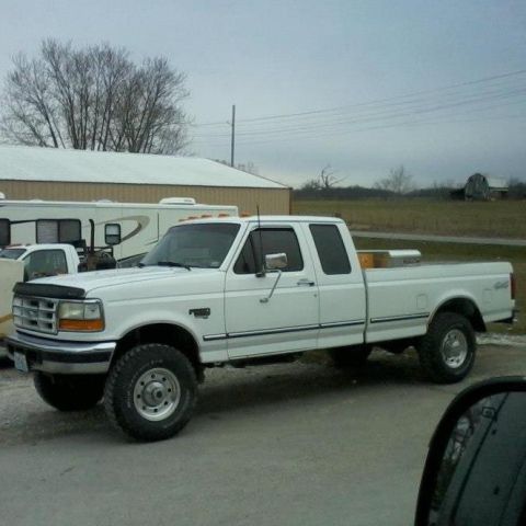 1987 Ford Bronco - This white Ford F-250 truck is parked in front of a building on an overcast day.