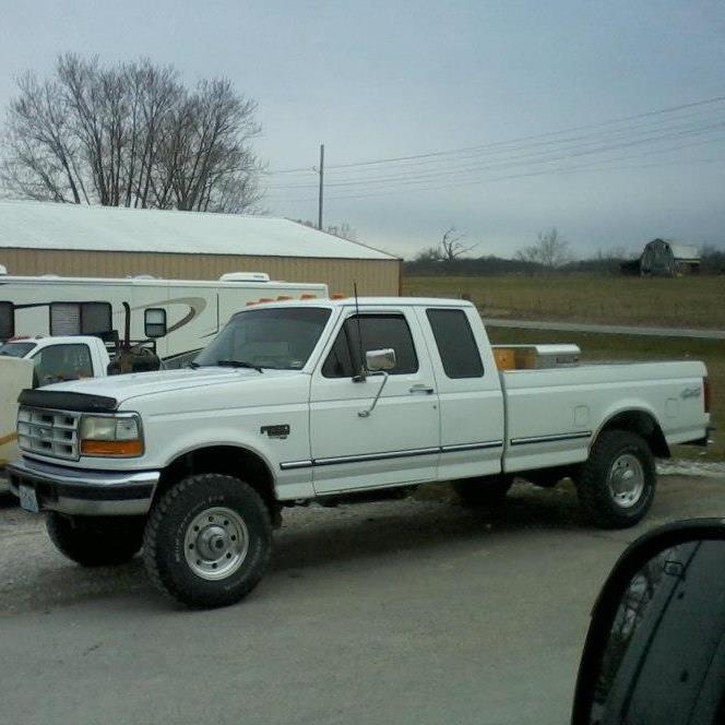 White Ford F-250 truck parked outside with a trailer behind it