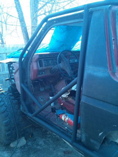 1986 Ford Bronco - Interior view of a modified Ford Bronco, showing a roll cage and dashboard.