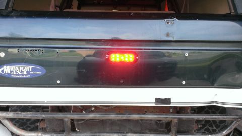 1994 Ford Bronco - Rear view of a Ford Bronco tailgate showing an aftermarket LED brake light and a 'Midnight 4x4' decal.