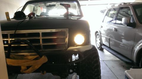1994 Ford Bronco - Front view of a 1994 Ford Bronco, modified with an aftermarket bumper and an auxiliary light, parked next to another SUV.