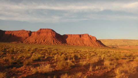 1994 Ford Bronco - Red rock mesas and dry grass in a desert landscape at sunset.