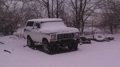 1979 Ford Bronco - A white 1979 Ford Bronco sits in a snowy yard during a snowfall.