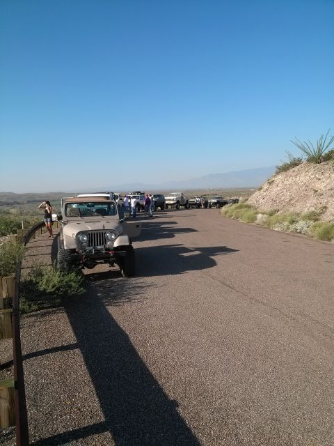 1981 Ford F-150 - Several Jeeps and trucks parked along a desert road on a clear day.