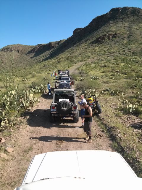 1981 Ford F-150 - A group of Jeeps on an off-road trail in a desert landscape, with people gathered near the vehicles.