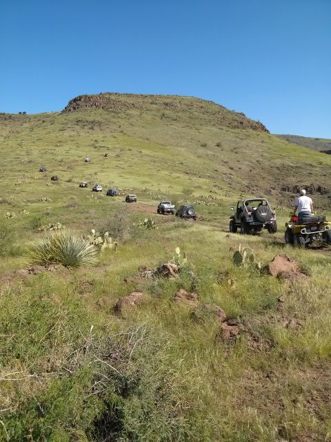 1981 Ford F-150 - A group of off-road vehicles, including Jeeps and an ATV, navigate a trail on a grassy hillside.