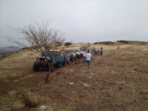1981 Ford F-150 - A group of off-road vehicles are gathered on a dirt path in a hilly, arid landscape.