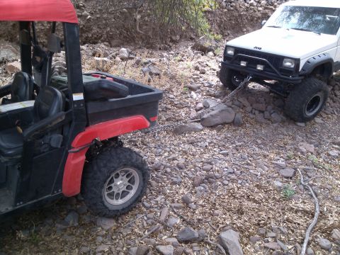 1981 Ford F-150 - A white Jeep Cherokee tows a red and black ATV on a rocky, off-road trail.