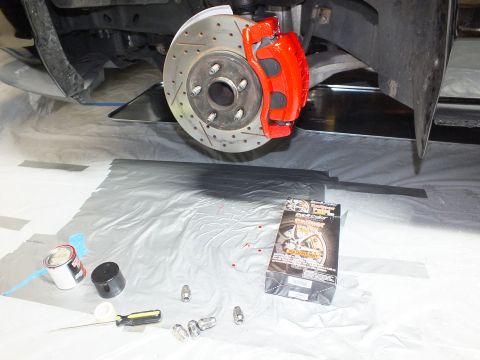 2003 Ford Crown Victoria - Red caliper over a drilled-slotted rotor on a black car, with a caliper paint kit laid out below.