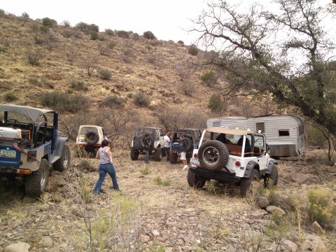 1981 Ford F-150 - A group of off-road vehicles and a trailer are gathered in a dry, hilly landscape.