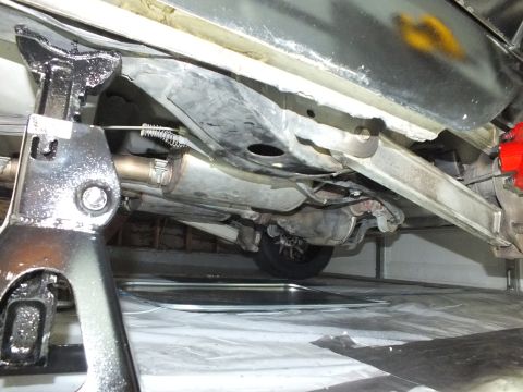 2003 Ford Crown Victoria - Exhaust pipe and rear suspension components viewed from beneath a vehicle on a jack stand.