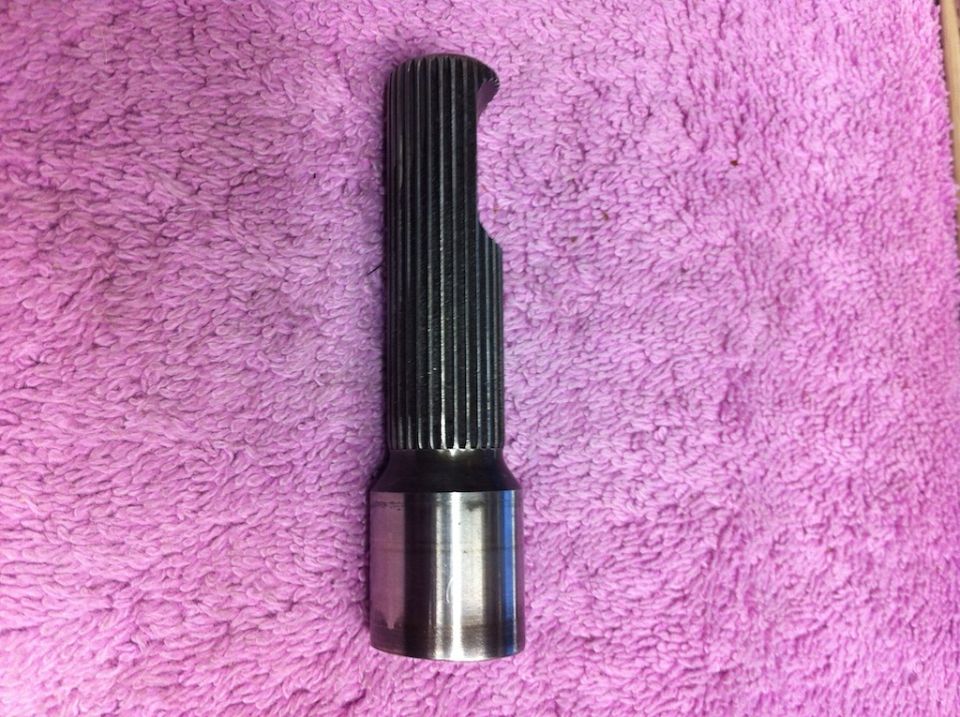 Metal splined shaft with a cut-out section, resting on a pink fuzzy surface